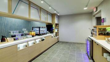 Eine moderne Hotellobby mit einer langen Rezeption, einer Kaffeemaschine und einem kleinen Kühlschrank.
