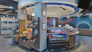 A self-service kiosk with snacks and beverages, a refrigerated display, and a counter with a digital screen.