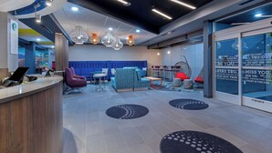A modern lobby with a reception desk, seating areas, and a large window with motivational quotes.