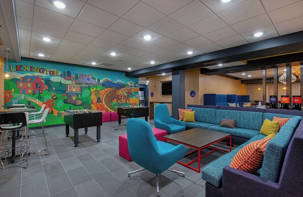 Un vestíbulo lleno de color con un mural, zonas de estar y una mesa de fútbol de mesa.