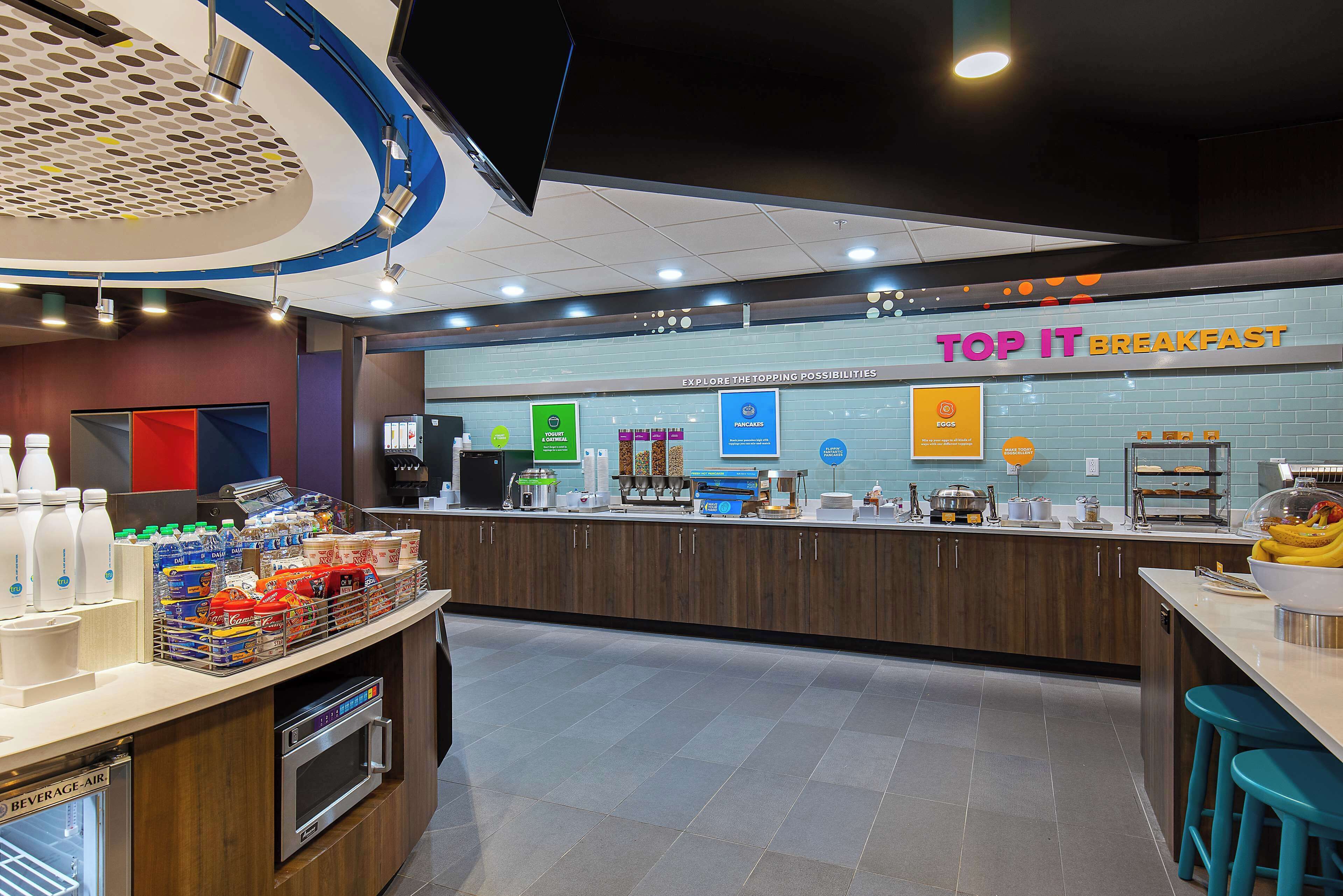A breakfast area with a counter displaying various food items and a sign reading "TOP IT BREAKFAST".
