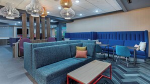 A modern lounge area with a blue sofa, a wooden coffee table, and a blue couch.