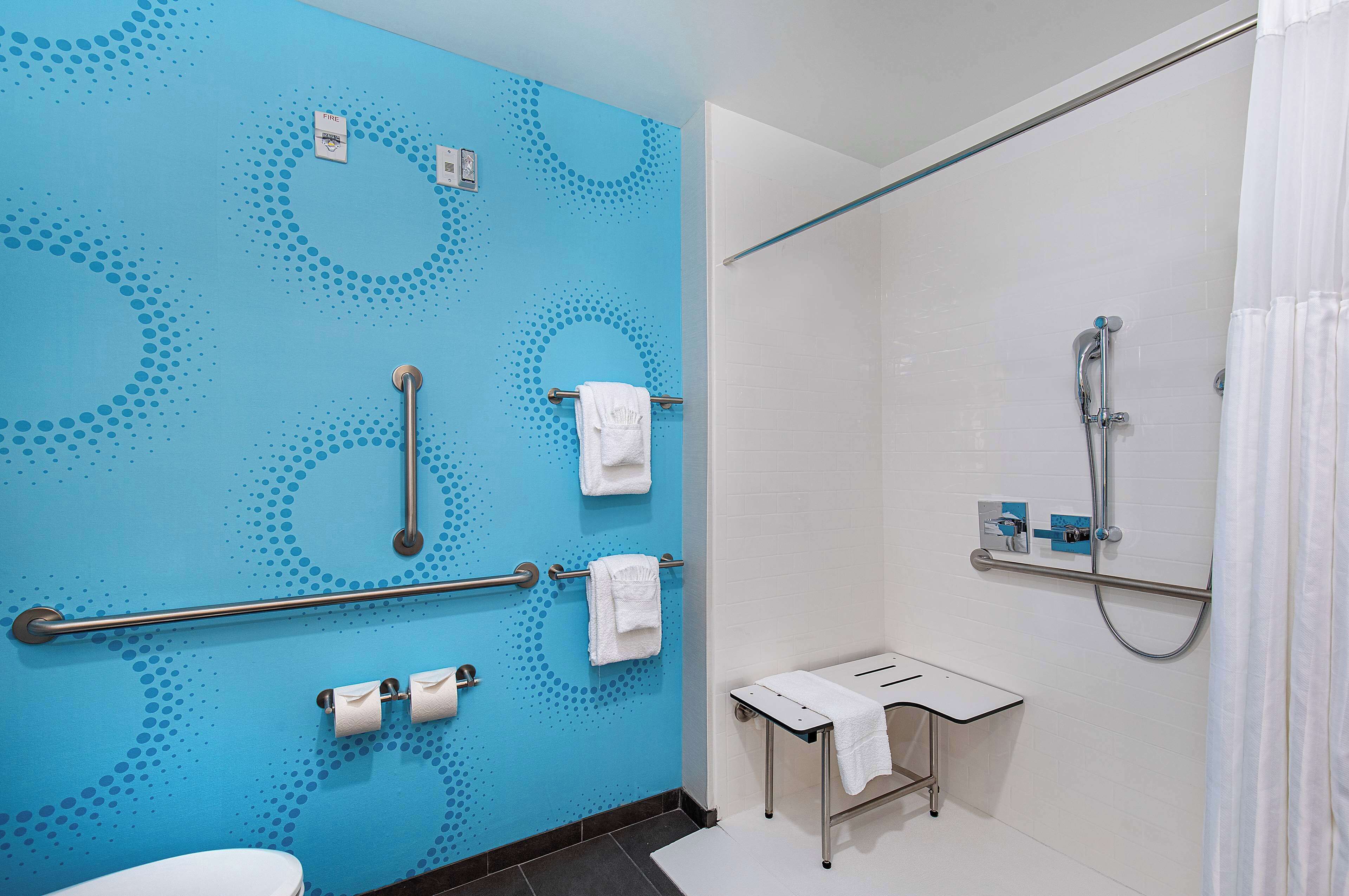 Un baño con pared azul, ducha, inodoro y lavabo.