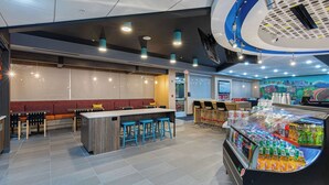A modern restaurant interior with a bar area, seating, and a beverage display.