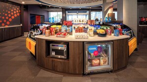 Un espace de libre-service où l’on peut se servir des boissons, équipé d’un réfrigérateur et d’un four à micro-ondes, et entouré d’un assortiment de collations et de boissons.