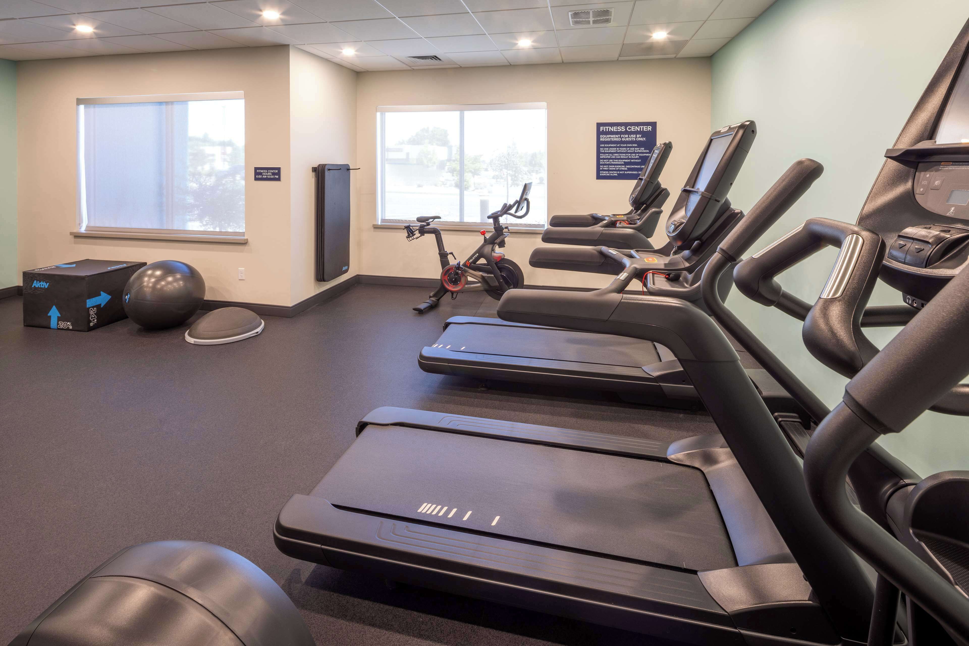 A fitness center with treadmills, stationary bikes, and exercise balls.