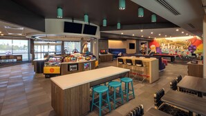 Un hall d’hôtel moderne avec un bar, des espaces de détente et une table de billard.