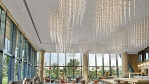 Un vestíbulo amplio con una gran zona de estar, un bar y ventanas panorámicas con vistas al exterior.