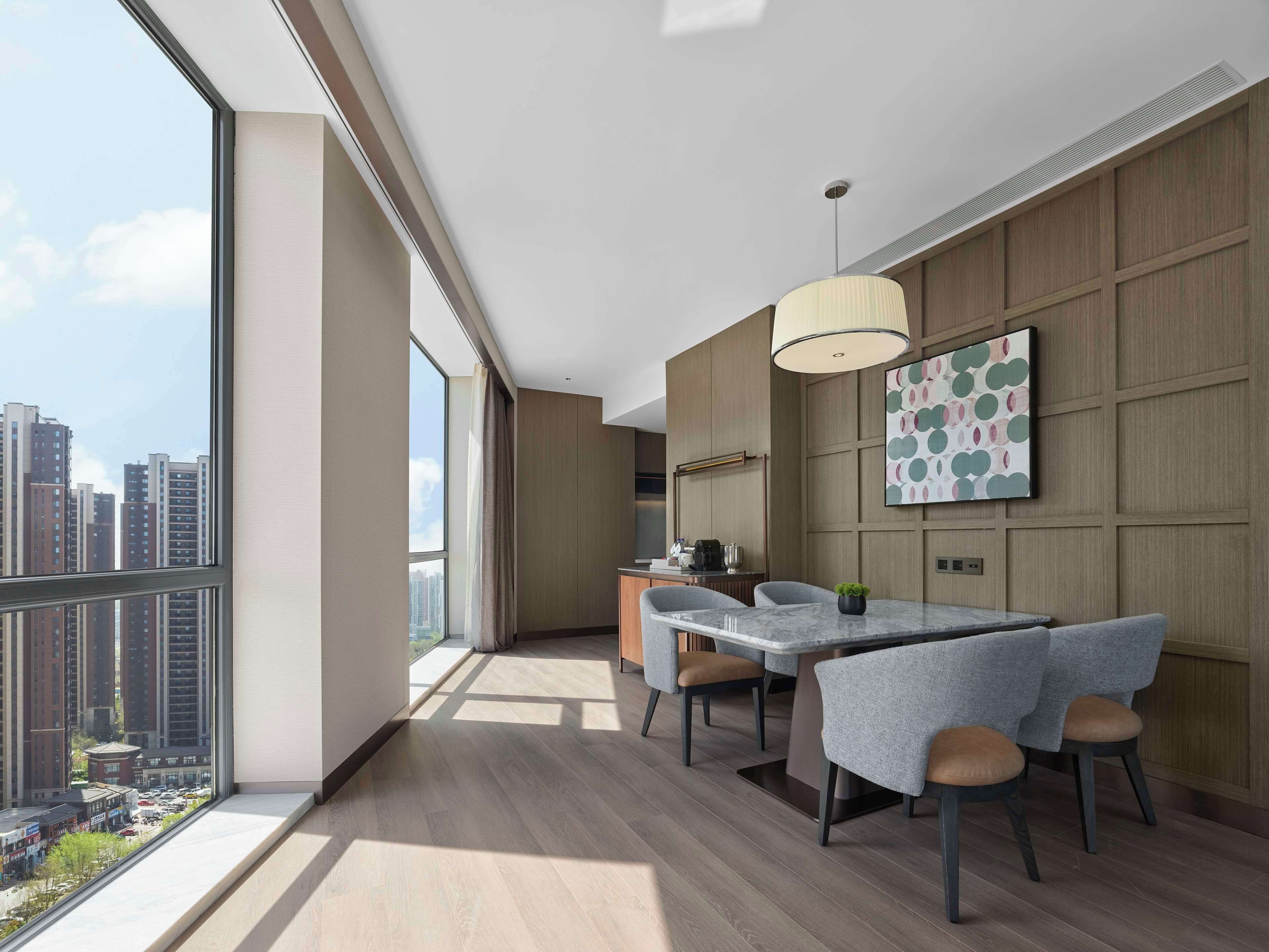 A modern kitchen with a dining area, large windows, and a city view.