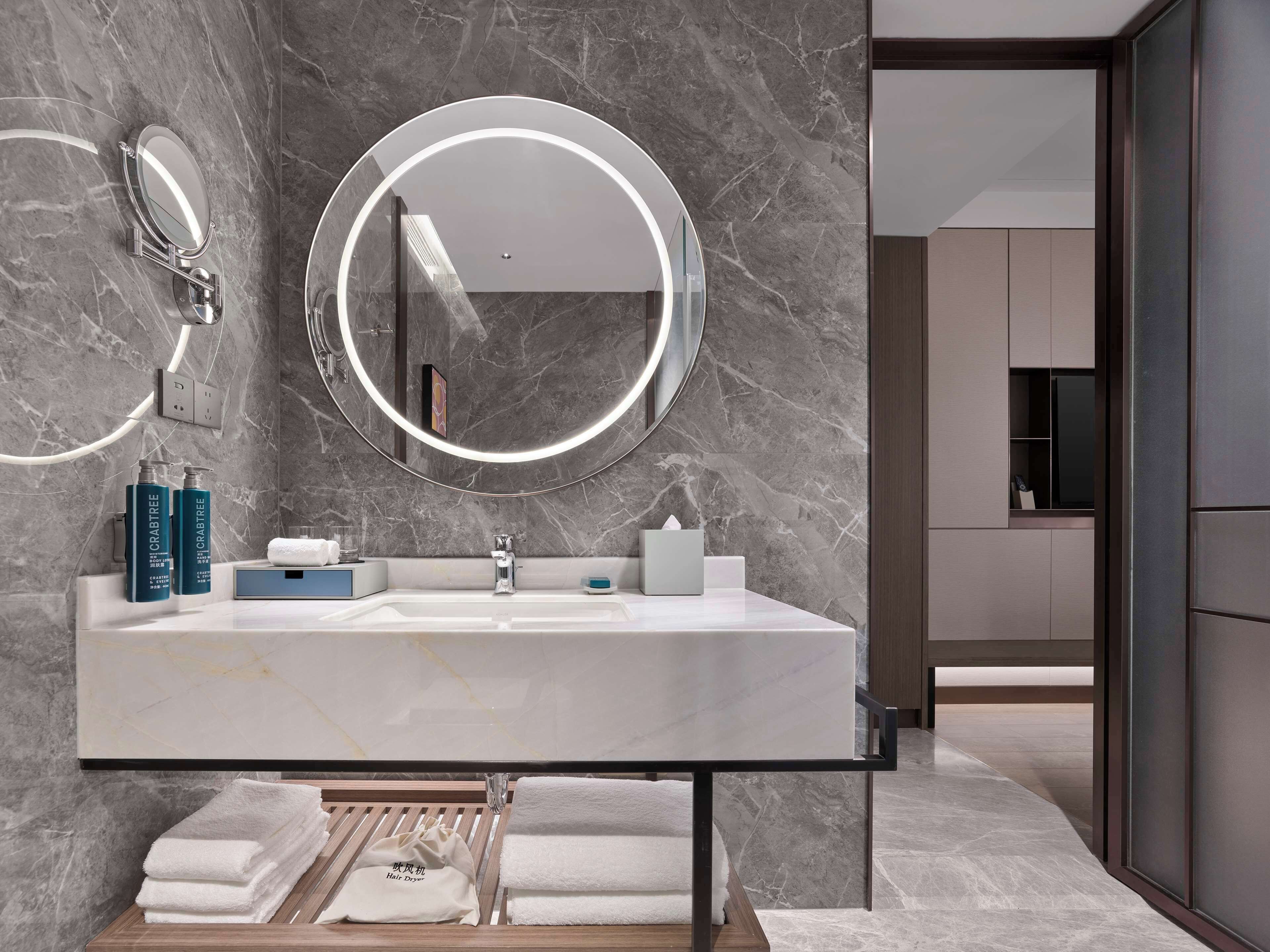 A modern bathroom with a marble sink, two mirrors, and a hairdryer.