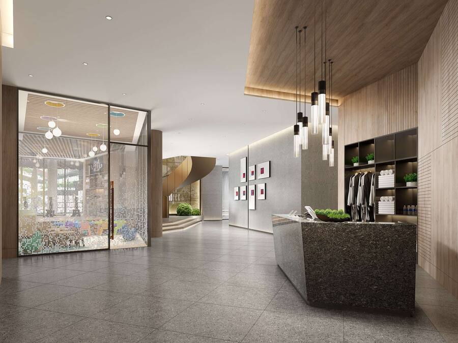 A modern lobby with a reception desk, wooden paneling, and hanging pendant lights.