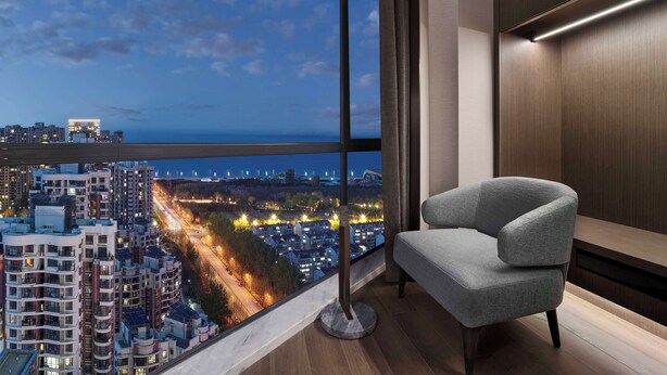 Habitación moderna con un ventanal amplio que ofrece vistas a la ciudad al atardecer.