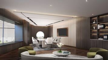 A modern meeting room with a round table, white chairs, and a large window with blinds.