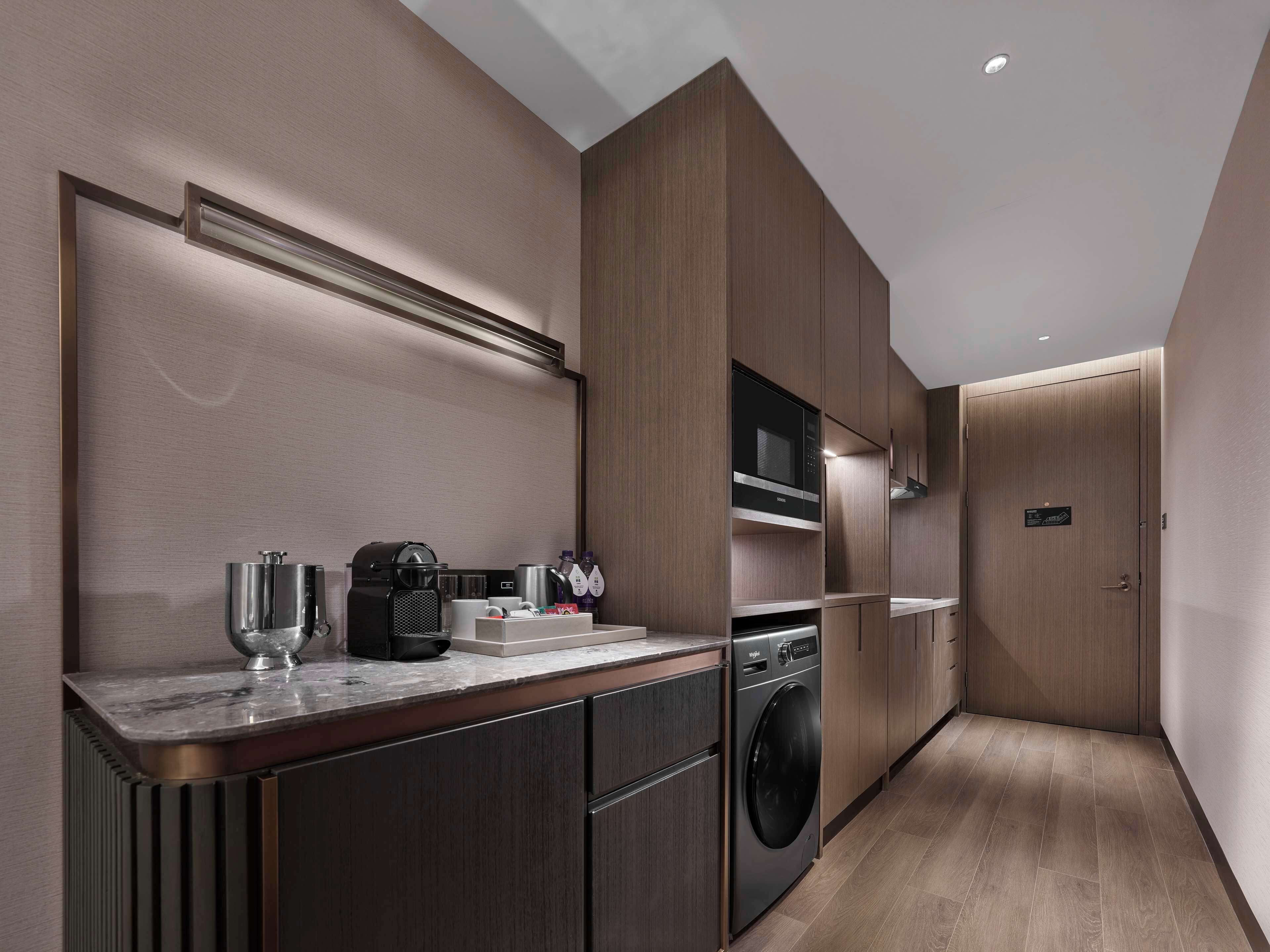 A modern kitchen with built-in appliances, a marble countertop, and wooden cabinetry.