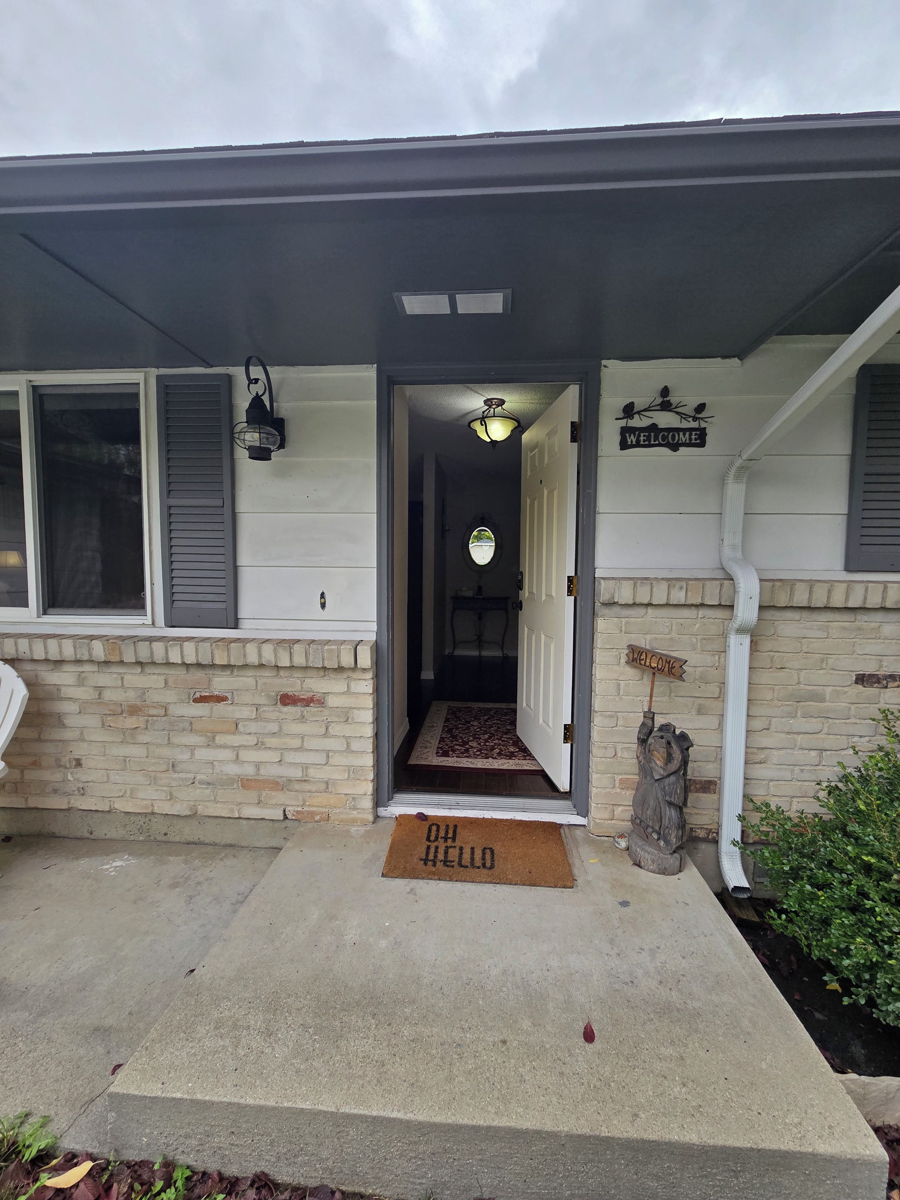 A house entrance with a welcome sign, a doormat, and a pathway leading to the door.