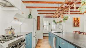 A kitchen with blue cabinets, a wooden floor, and hanging plants.