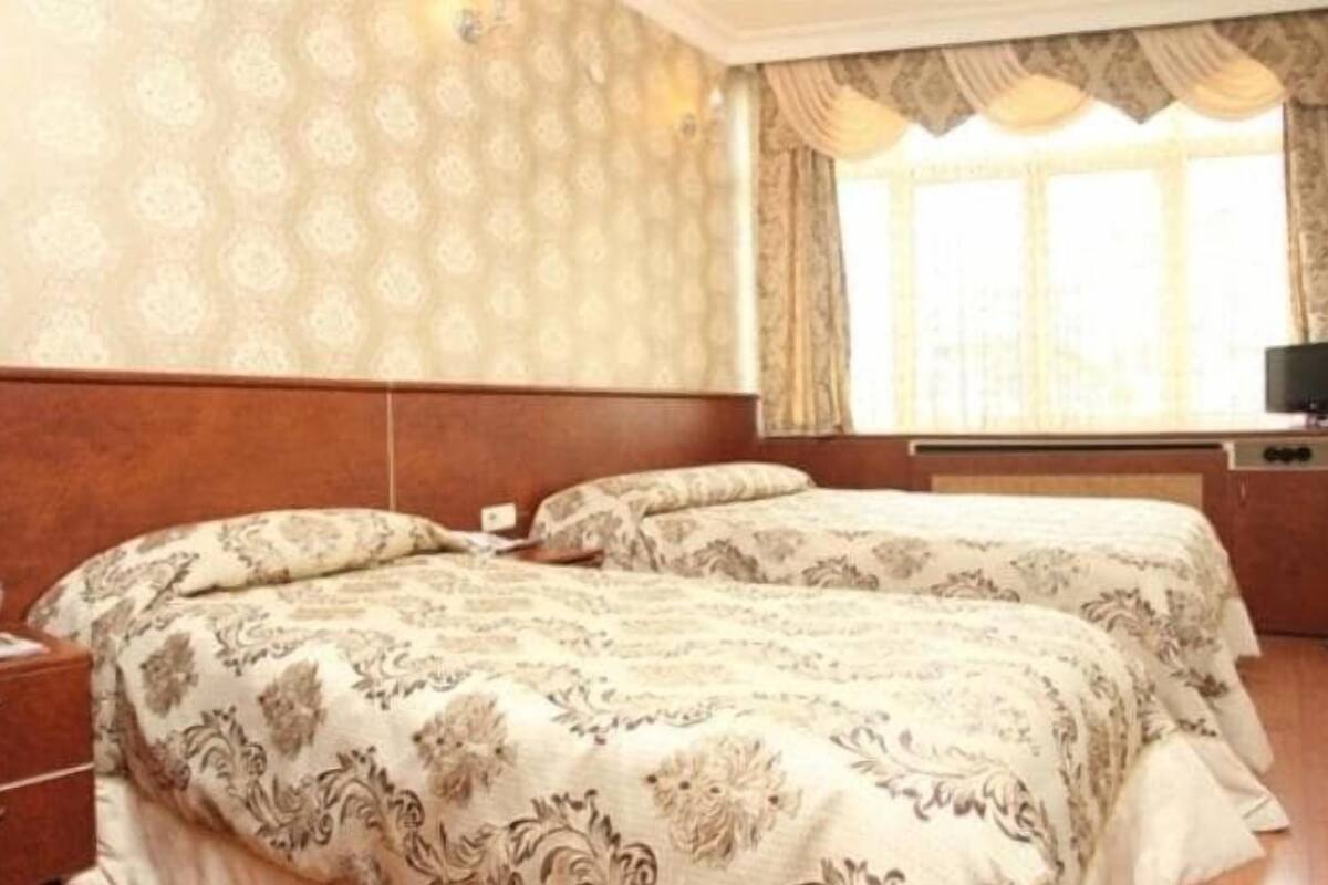 A hotel room with two beds, a TV, and a dresser.