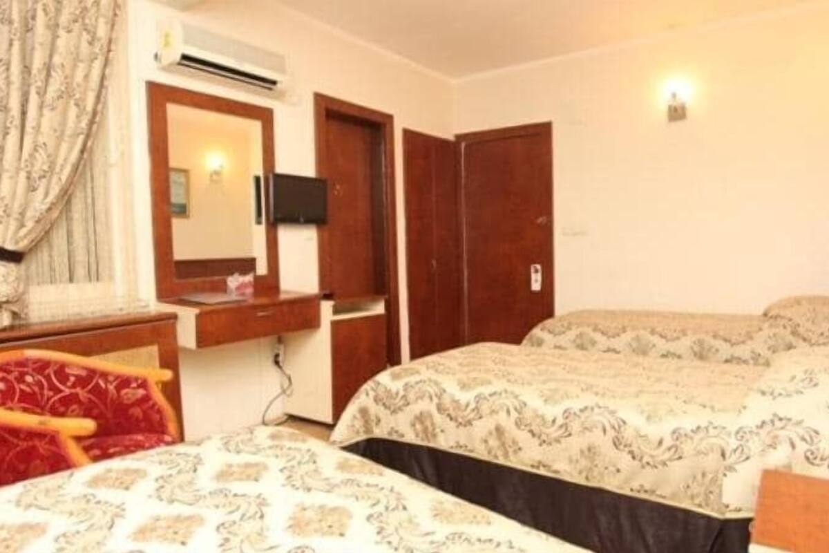 A bedroom with two beds, a mirror, a desk, and a wardrobe.