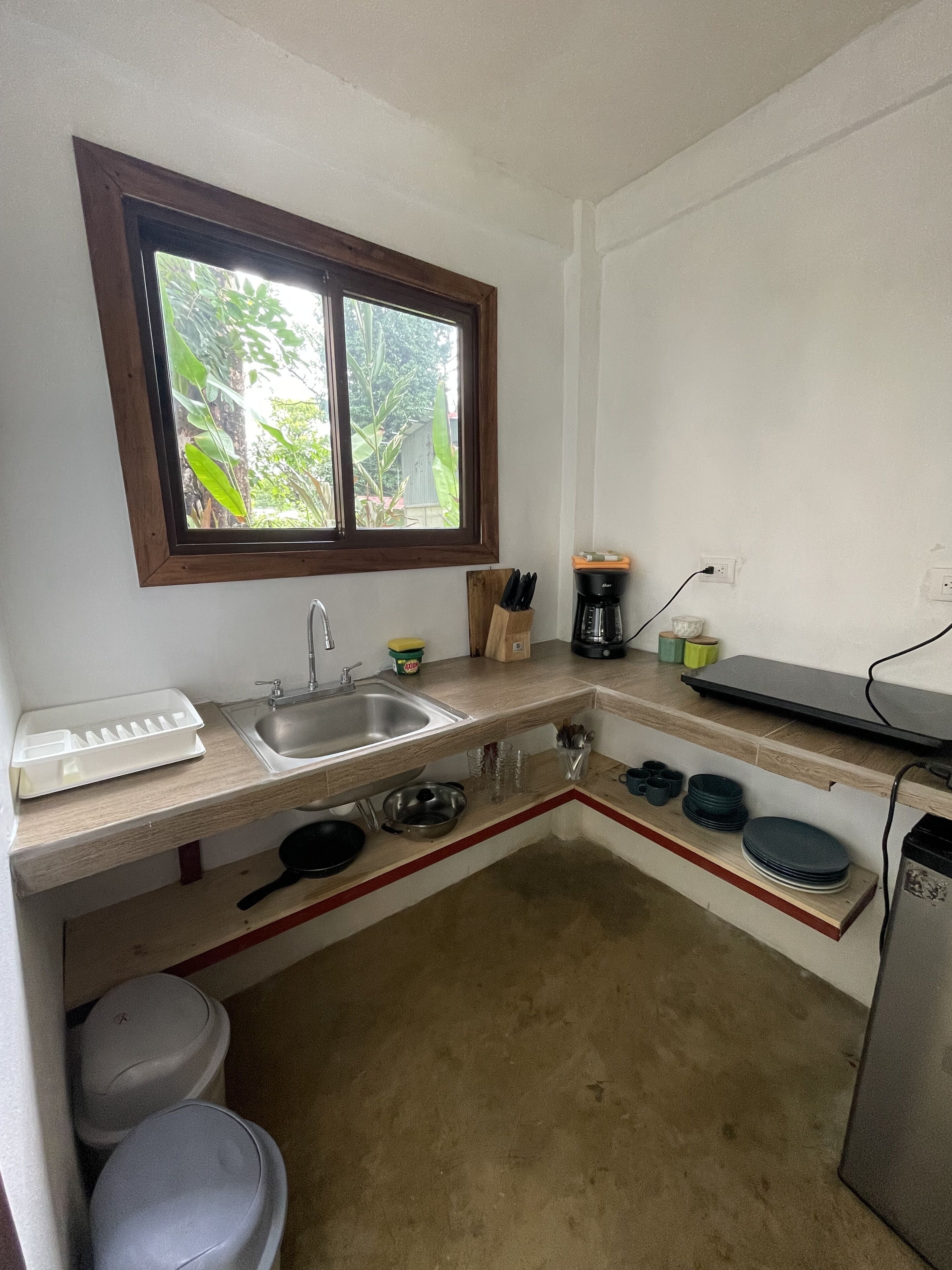 A compact kitchen with a window, sink, and basic appliances.