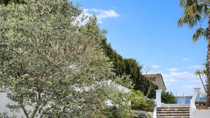 A stone pathway leading to a white-walled building with a staircase.