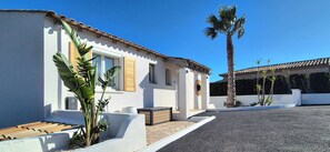 A modern house with a white exterior, a tiled roof, and a palm tree.