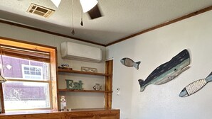 A dining area with a round table surrounded by chairs, wooden cabinets, and a window with blinds. - Waterfront 2 Bedroom/Duplex H/Remodeled 2024 (Grove)