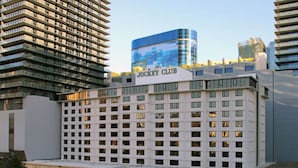 A multi-story hotel with a prominent "Jockey Club" sign, featuring a modern glass facade and a traditional building facade.