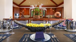 Una mesa de comedor dispuesta con un centro de flores amarillas, copas de vino y cubiertos.