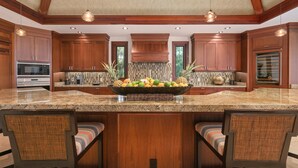 Una cocina amplia con armarios de madera, encimeras de granito y una isla central con un bol de frutas.