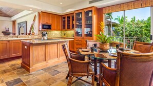 Un'ampia cucina con mobili in legno, una grande isola e un'area pranzo con sedie in vimini.