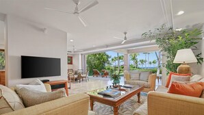 Uma sala de estar ampla com televisão de tela plana, assentos confortáveis, uma mesa de centro e vista para o exterior.