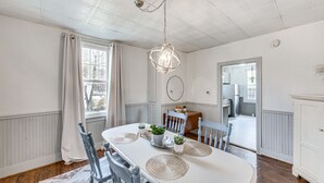 Ein Esszimmer mit weißem Tisch, grauen Stühlen und einer Pendelleuchte.