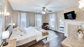 Ein Schlafzimmer mit einem Bett, einem Sessel, einem Fernseher und einem Kamin.