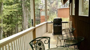 Un espacio al aire libre cubierto con una parrilla, dos sillas y una mesa.