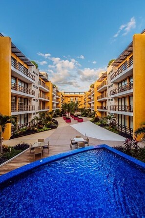 Um hotel com um pátio central, piscina e várias varandas.