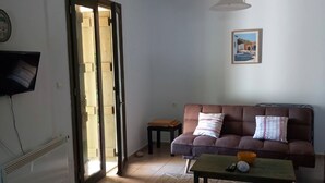 Ett vardagsrum med en soffa, ett soffbord, en tv och en dörr som leder ut.