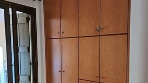 Ett sovrum med en stor garderob i trä, en säng med ett quiltat madrass och en skjutdörr i glas som leder ut till ett utomhusområde.