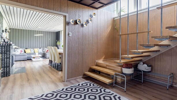 Un interior moderno con una escalera, paredes de madera y un comedor.