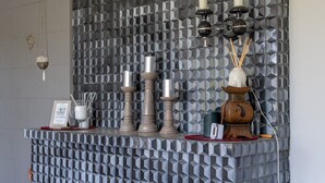 Una pared decorativa con patrones geométricos, un candelabro y una pequeña señal con información de la contraseña de Wi-Fi.