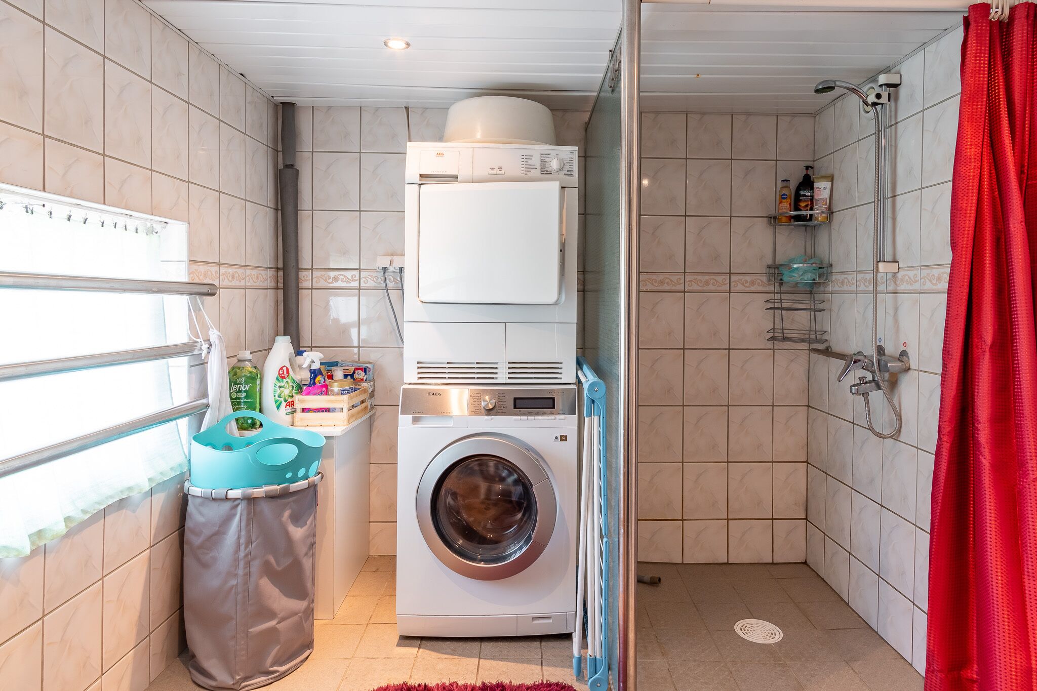 Une petite buanderie comprenant un lave-linge, un sèche-linge et des armoires superposées.