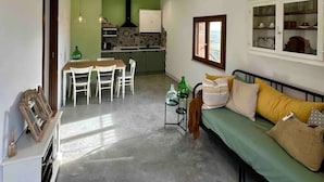 A compact living space with a dining area, kitchenette, and a sofa with cushions. - Suite Gioconda - Podere Casa Rossa in Pienza (Pienza)