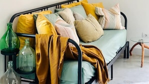 A bed with a mustard blanket, multiple pillows, and two glass bottles on a metal stand. - Suite Gioconda - Podere Casa Rossa in Pienza (Pienza)