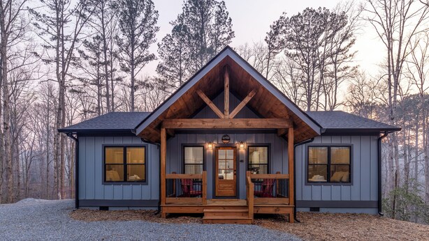 A cabin with a wooden front porch, two windows on each side, and a gravel driveway. - River View Getaway by 2DC (Gilmer County)