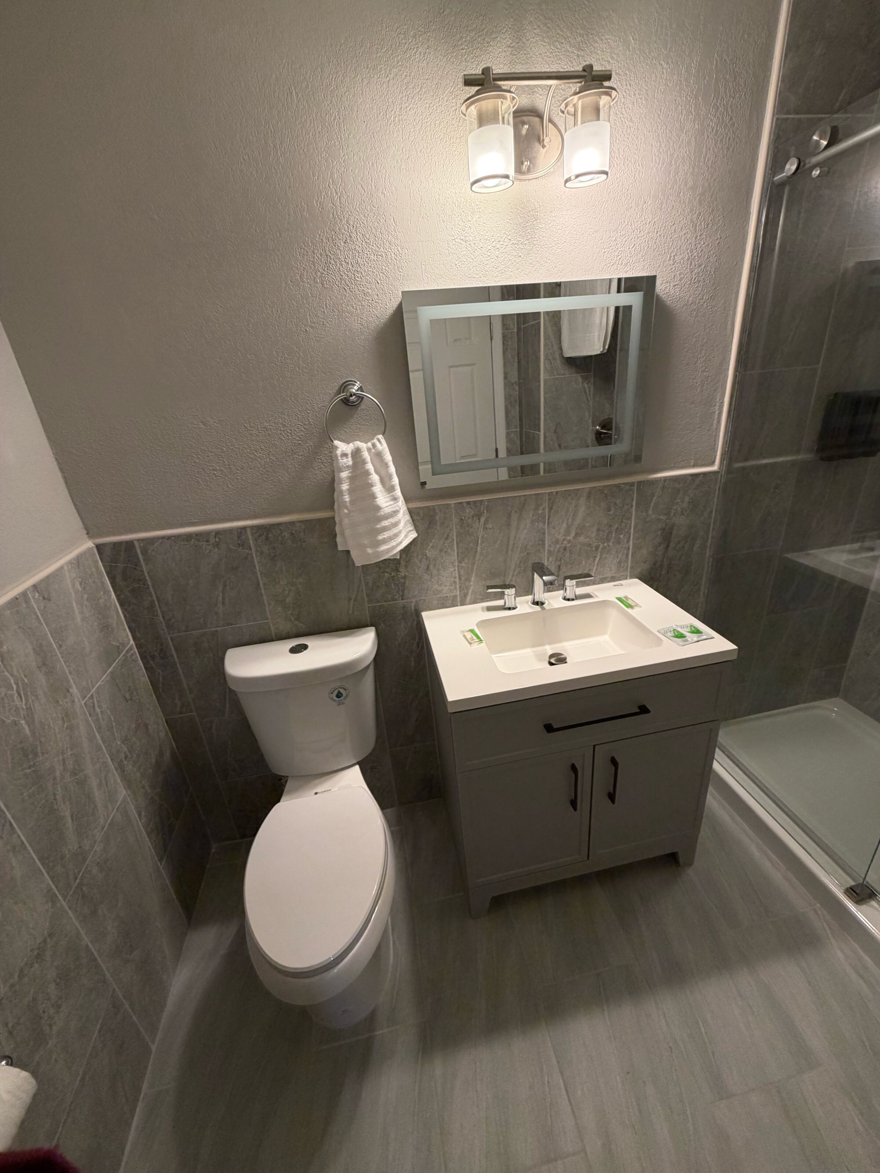 A modern bathroom with a toilet, sink, vanity, and shower.