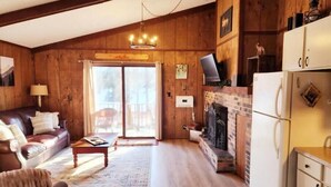 A cozy living room with a fireplace, wooden walls, a sofa, and a television. - Cozy 3BR Ski-Chalet Style Retreat w/ Sauna + Fireplace— Outdoor Adventure Base (Bessemer)