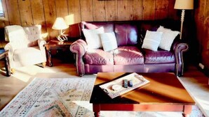 A cozy living room with a purple leather sofa, a wooden coffee table, and a patterned rug. - Cozy 3BR Ski-Chalet Style Retreat w/ Sauna + Fireplace— Outdoor Adventure Base (Bessemer)