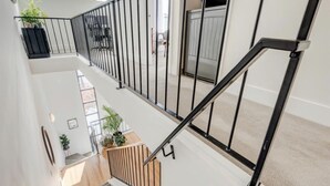 Ein mehrgeschossiges Interieur mit Treppe, weißen Wänden und schwarzen Geländern.