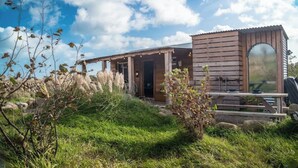Eine Holzjagdhuette mit überdachter Veranda, einer kleinen Außen-Sitzgelegenheit und einem großen Fenster.