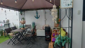 An outdoor patio with a table and chairs, a speaker, and various decorative items.