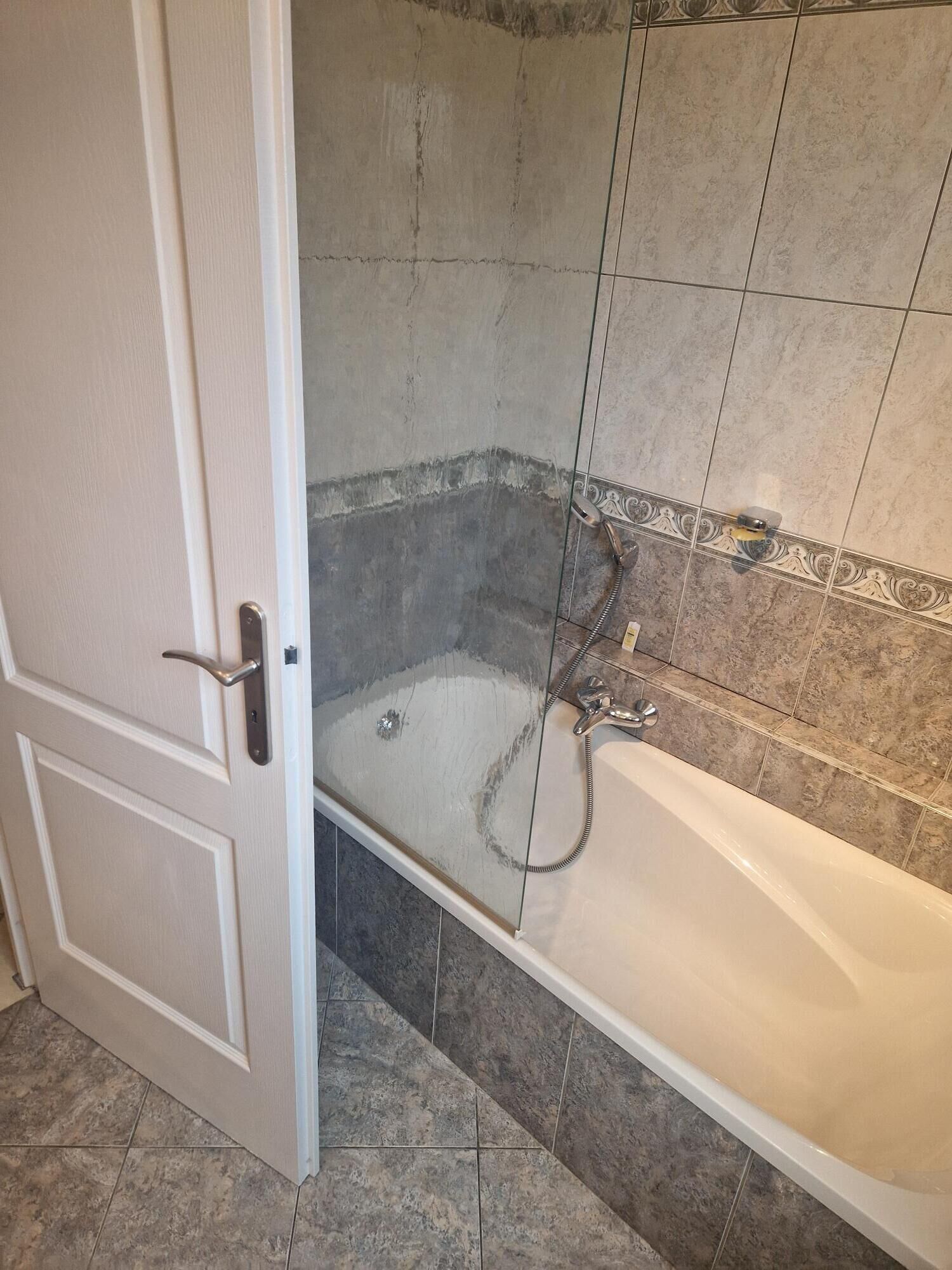 A bathroom with a bathtub, shower, and a door.